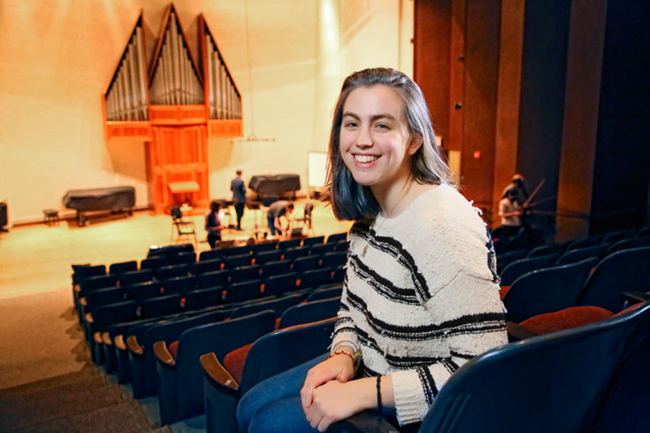 Liana sitting in a theater with the stage in the background