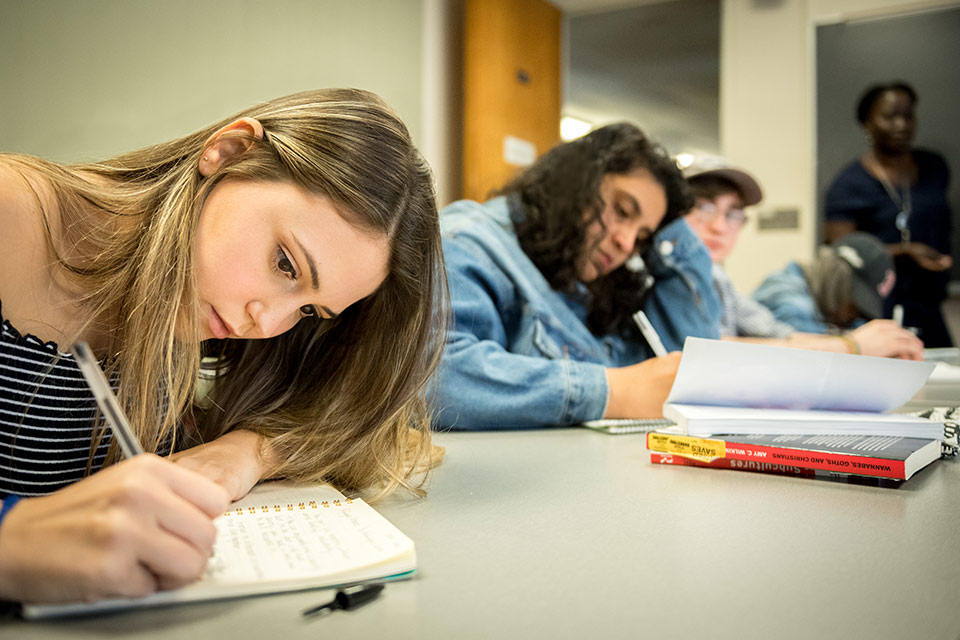 Students writing in class with Prof. Diouf