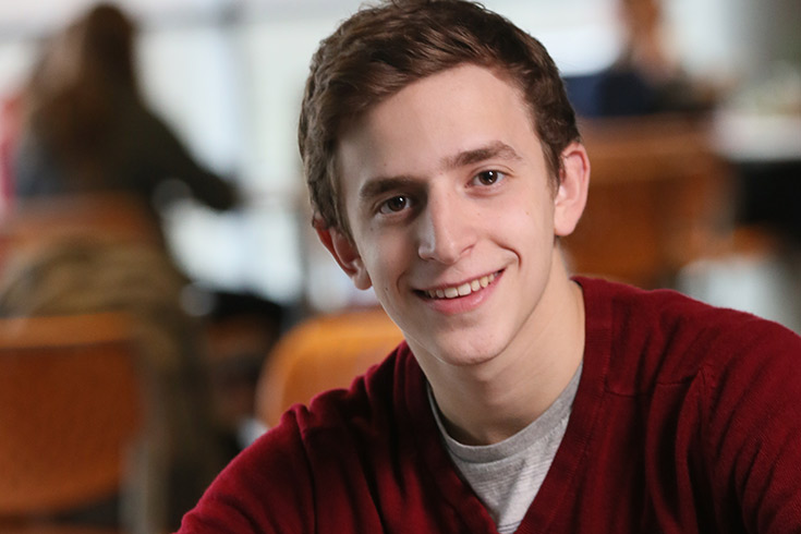 Seth smiles while seated indoors