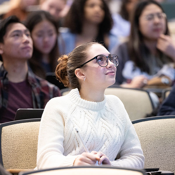 A student taking notes in a lecture hall