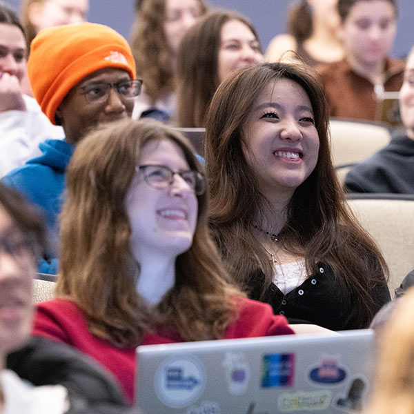 Three students laugh while sitting at a table in the library