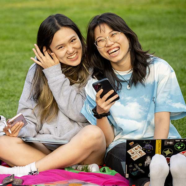 Two smiling students looking at a phone