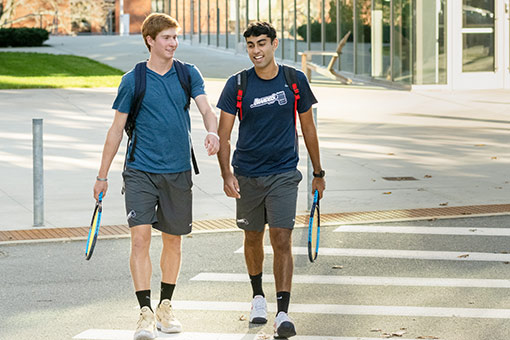 Two students walking with tennis rackets