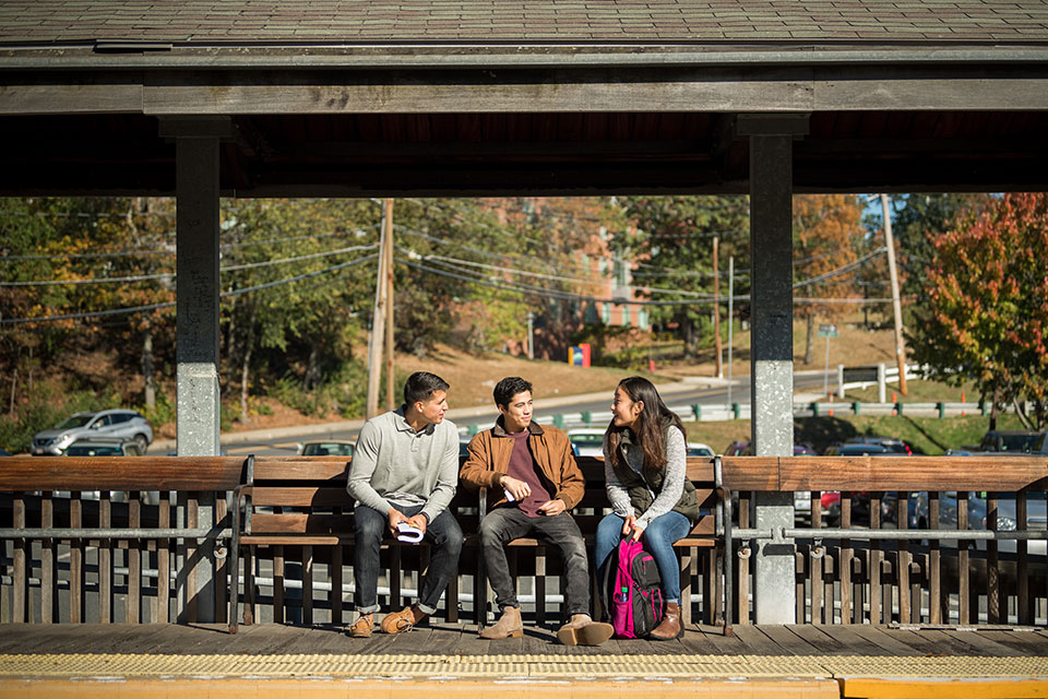 Students sit and chat on a bench at the train station