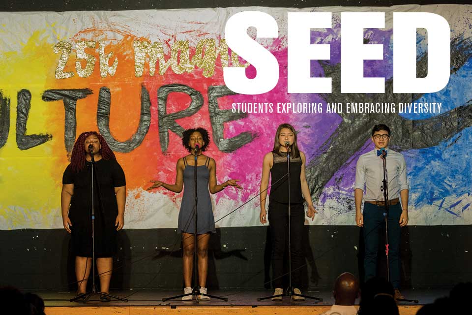 Four students on stage with a colorful background at the CultureX show