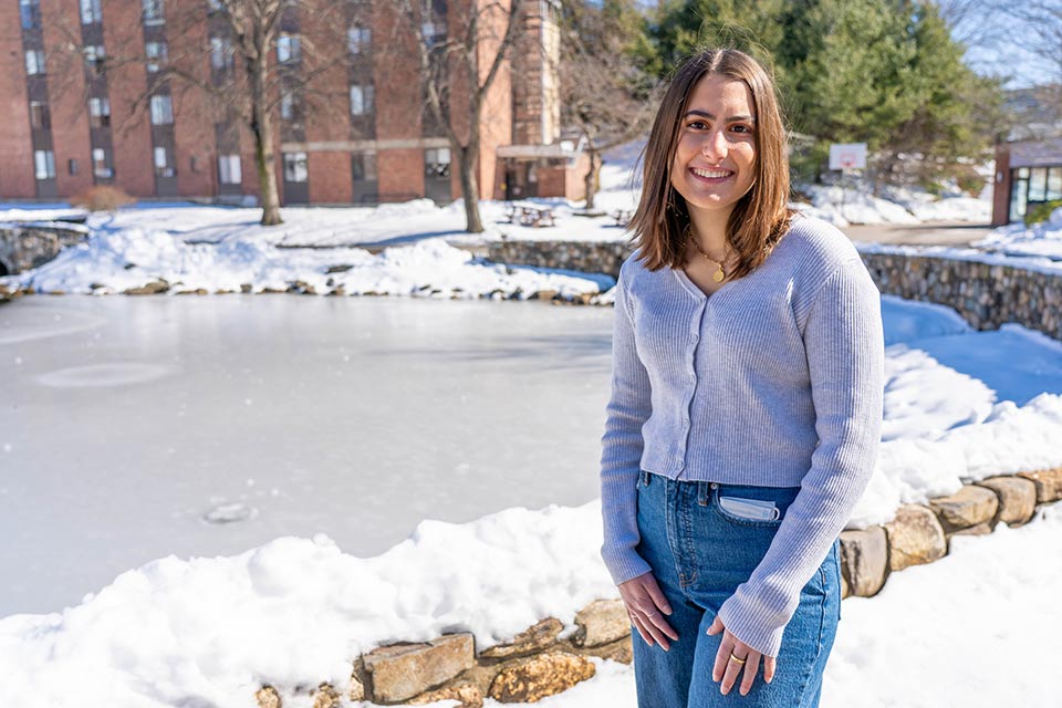 Susanna smiling at the camera and standing in front of snowy Massell Pond.