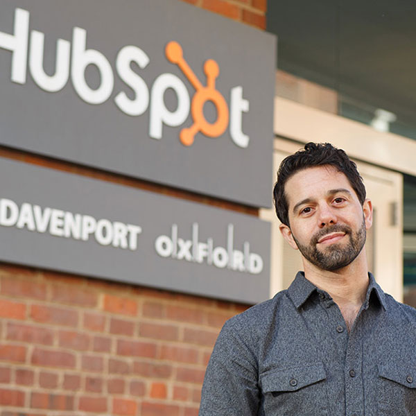 Sam standing outside an office building with the Hubspot logo on the side of the building