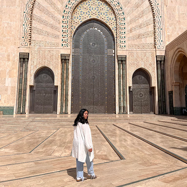 Amelia walks in front of an intricate doorway in Morocco