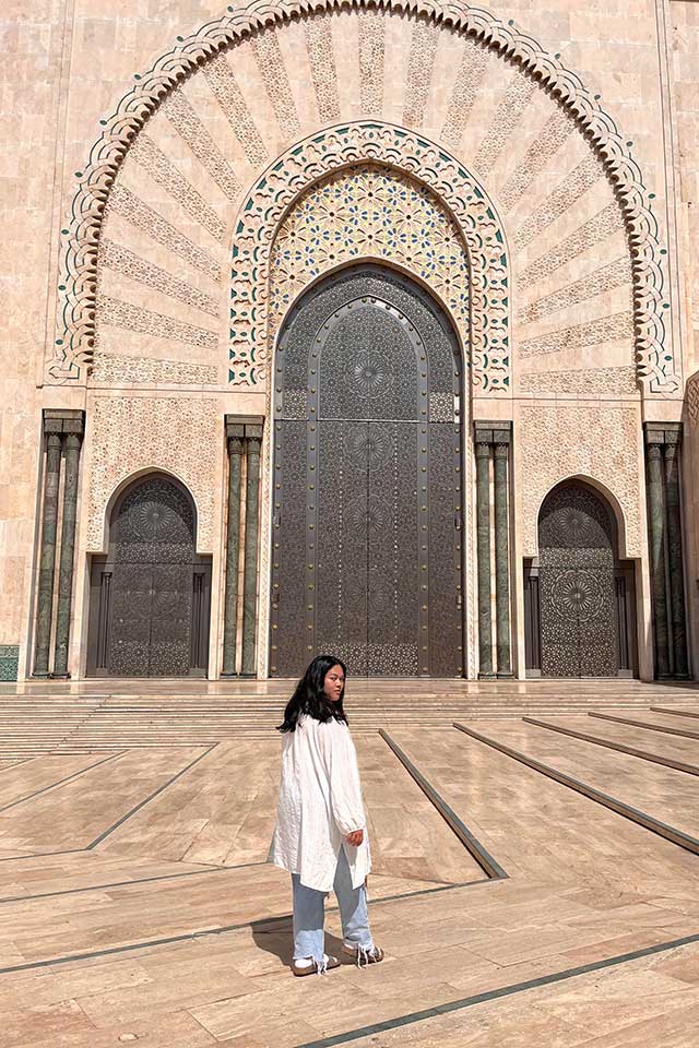Amelia walks in front of an intricate doorway in Morocco