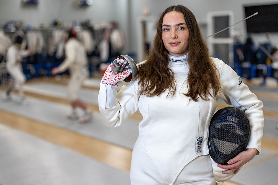 Bronwyn smiles while dressed in fencing gear.