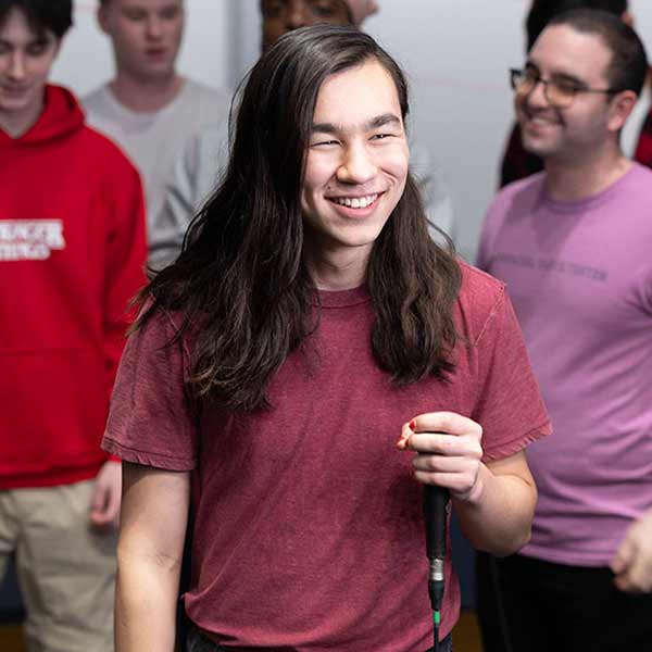 Devyn smiles while holding a microphone