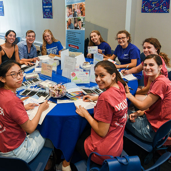 A group of students sits around a table working on a volunteer project