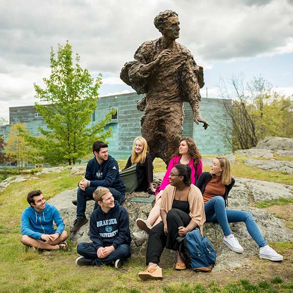 A group of students sits in front of the Louis Brandeis statue