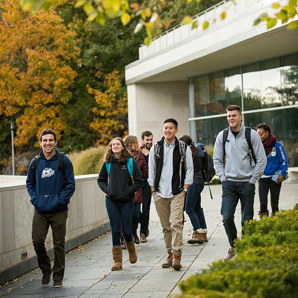 A group of smiling students walks by Shapiro Campus Center