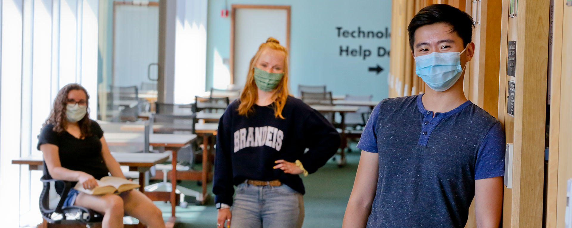 Students in masks stand socially distanced in the library.