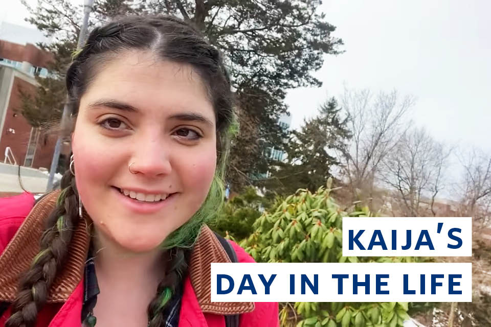 Kaija looks at the camera. The words Brandeis A Day in the Life of Kaija G. ’24 are on the right