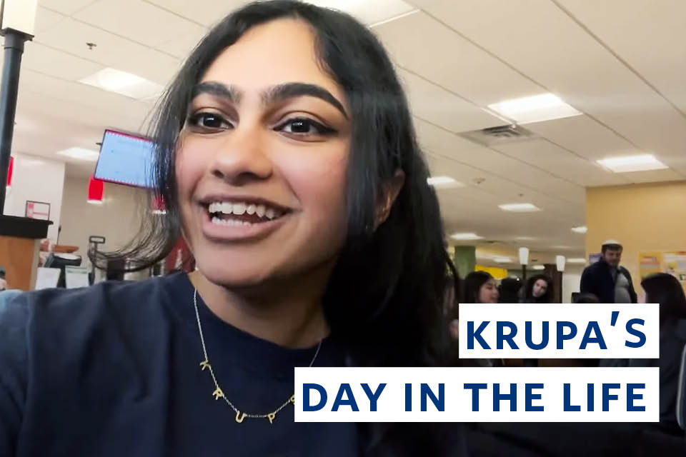 Krupa looks at the camera. The words Brandeis A Day in the Life of Krupa S. ’23 are on the right