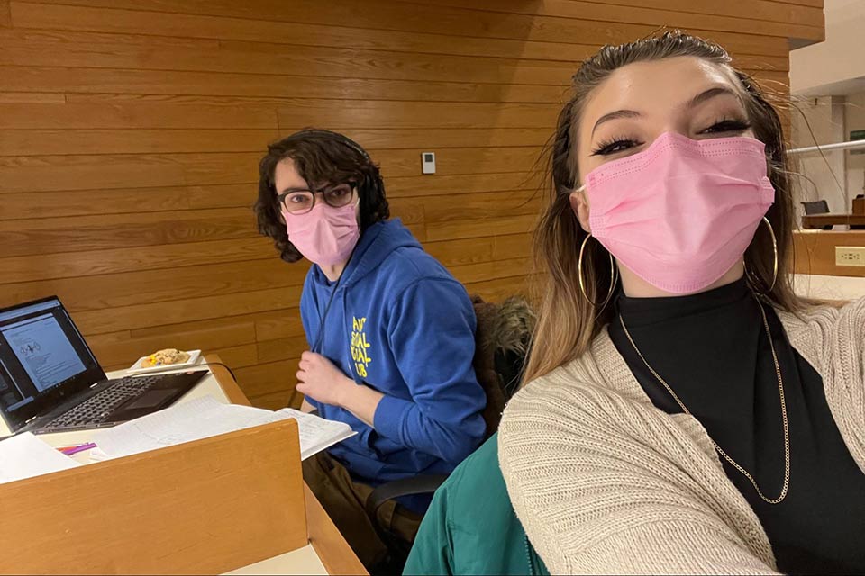 Madison and Cole at a table in the library. Both are wearing masks.