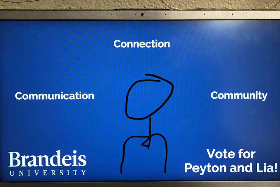 A blue screen with text reading communication, connection, community. Vote for Peyton and Lia! Brandeis University