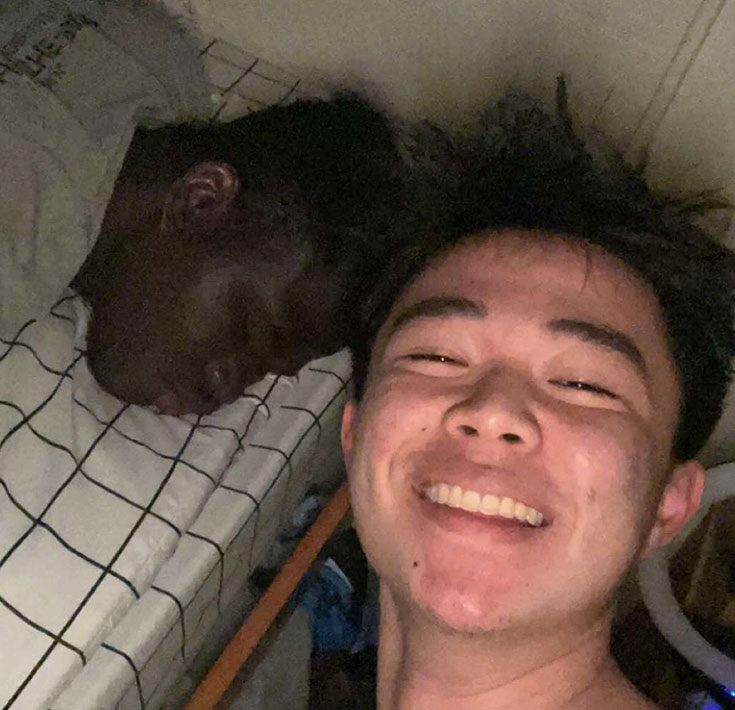 Marcus asleep and his roommate smiling at the camera
