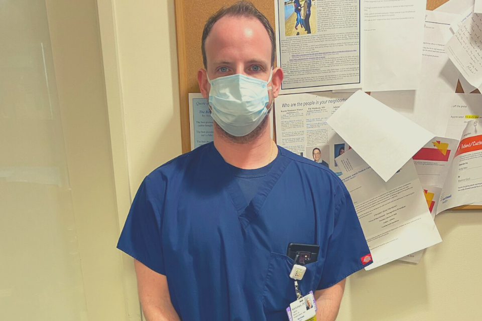 doctor wearing a face mask stands in front of bulletin board
