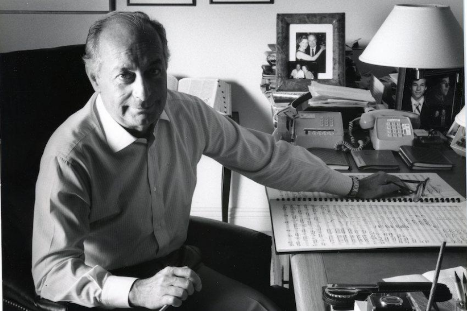 Henri Lazarof sitting at desk with sheet music