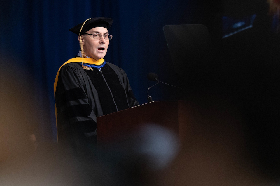 Drew Weissman stands at the podium at Commencement