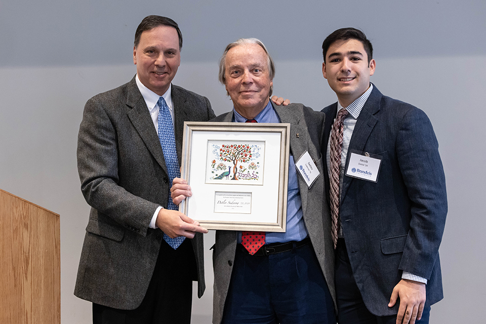 Brandeis University President Ron Liebowitz, 1970 graduate Detlev Suderow and 2024 graduate Jacob Zackai pose with Suderow's Lighting the Way award in a ceremony on March 30.