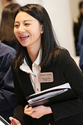 Woman, professionally dressed,  smiling and speaking to someone at a conference