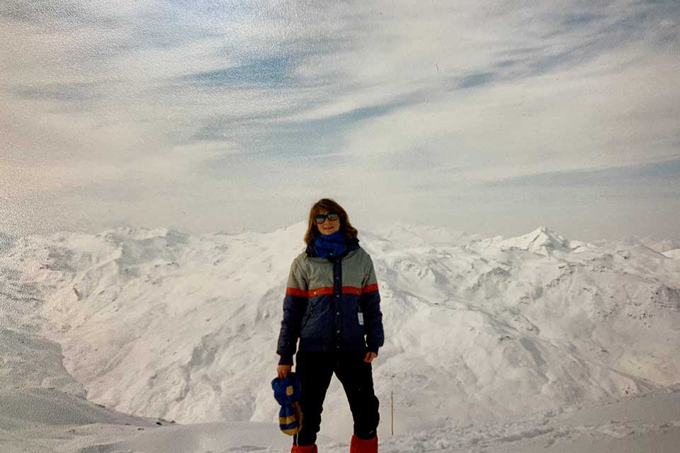 Mara Posner Metzger in snow gear standing in front of the Alps.
