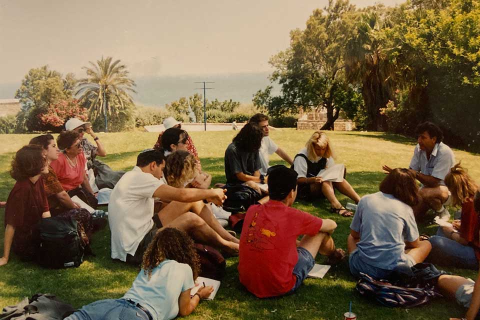 A group of students seated outside listening to an instructor in Israel. 