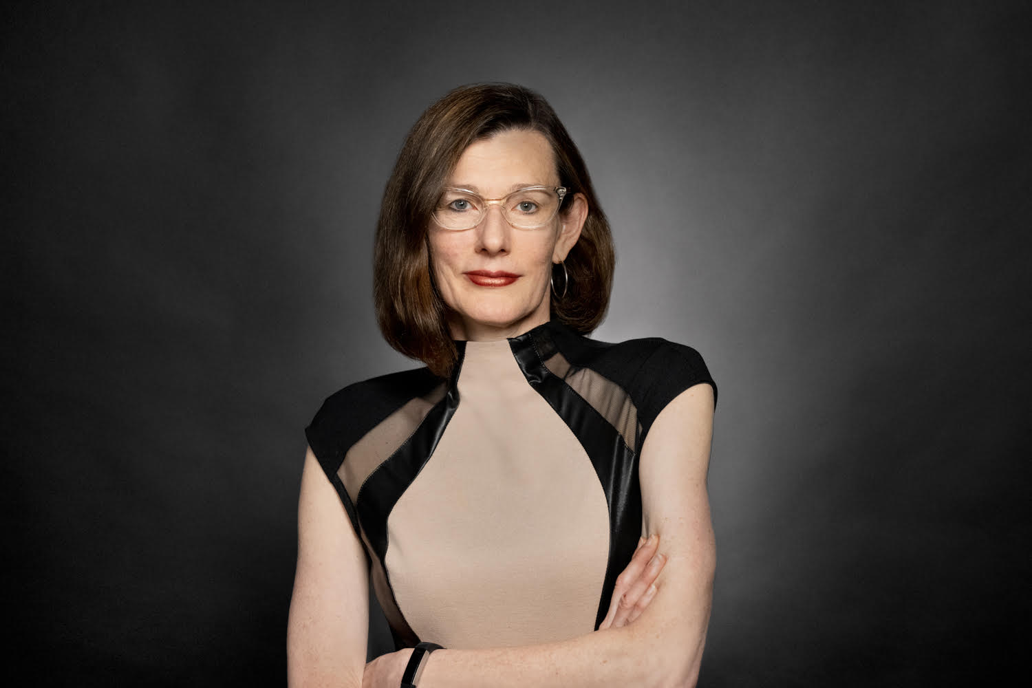 Heather Hendershot crosses her arms in front of a black background.