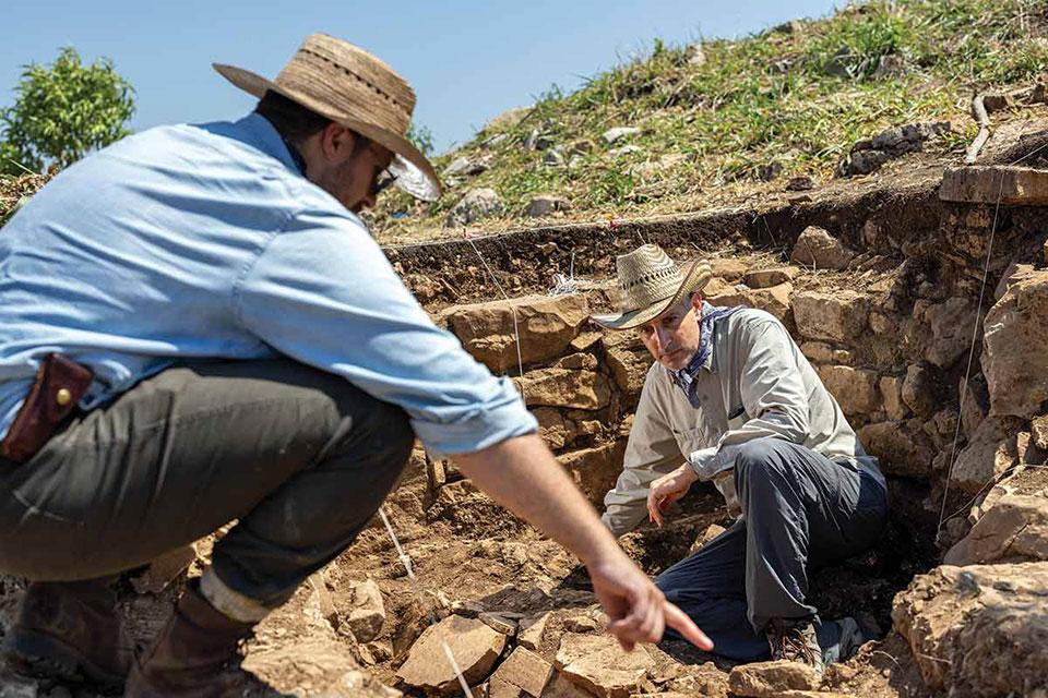 two anthropologists digging through ruins