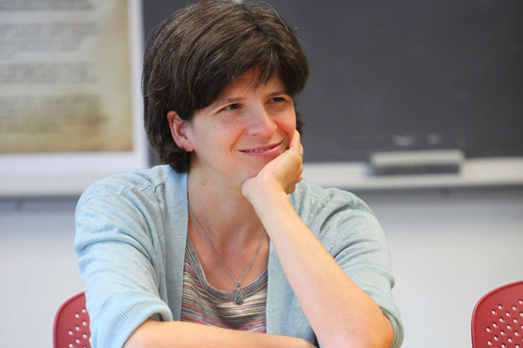 Elizabeth Ferry sits at a table smiling, chin in hand