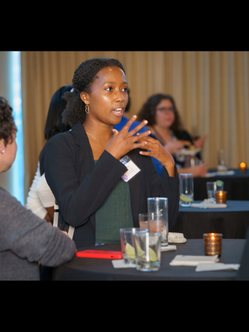 woman standing at a table at a conference, talking