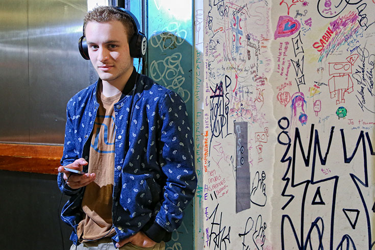 Marcelo Brociner, wearing headphones, stands in front of a wall that has been drawn on