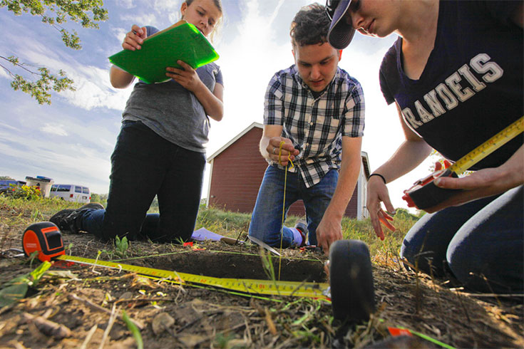 Students look into a hole in the ground
