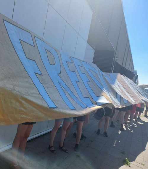 people holding a sign that says Freedom (the rest illegible)