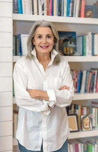 woman with arms crossed in front of bookshelf