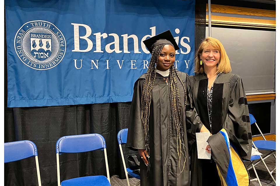student in commencement regalia beside professor