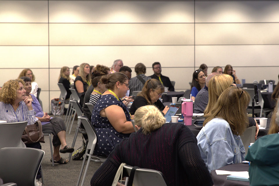 sideview of audience at tables listening