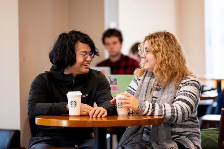 Two students chat over coffee