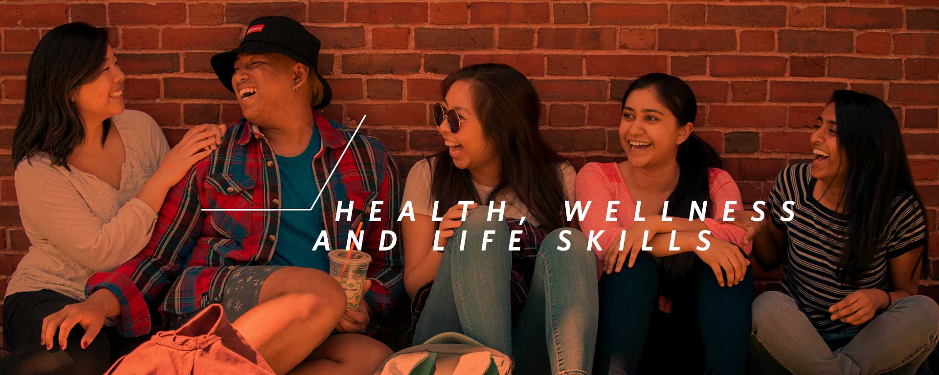 five students laughing while seated on couch against brick wall, overlaid by words health, wellness and life skills.