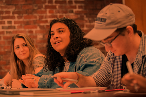 three students seated at table in classroom