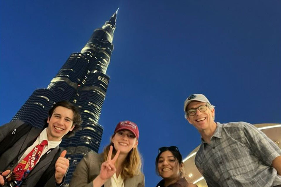 four people smile in front of a skyscraper in Dubai