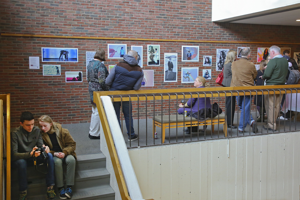 Exhibition of photos on a brick wall, people gathered