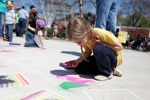 Youngster drawing on the cement with chalk near the Shapiro Campus Center.