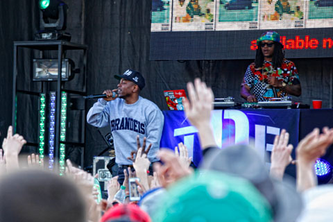 Kendrick Lamar wearing a Brandeis shirt, performing for the festival crowd.