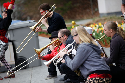 Horn players from the Hungry March Band crouched down while performing.