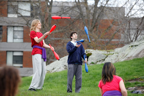 Two students juggling red and blue clubs.